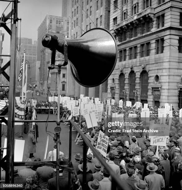 View of a crowd gathered on a Manhattan street during an anti-fascism demonstration, New York, New York, 1942. Many hold signs, some of which read...