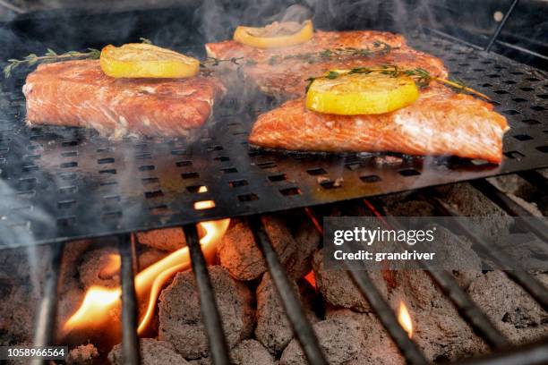 delicious salmon filets on a grill topped with lemon slices - grilled fish stock pictures, royalty-free photos & images