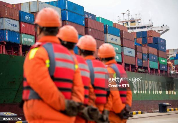 Employees look at a cargo ship at a port in Qingdao, east China's Shandong province on November 8, 2018. - China's exports to the US and the rest of...