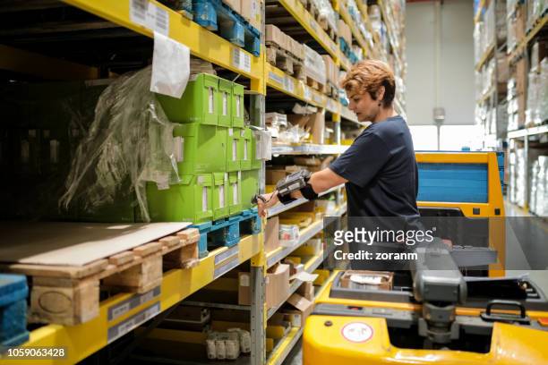 female workhouse worker holding bar code reader against products on shelfs - pallet jack stock pictures, royalty-free photos & images
