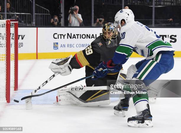 Marc-Andre Fleury of the Vegas Golden Knights knocks the puck away from Brandon Sutter of the Vancouver Canucks in the first period of their game at...