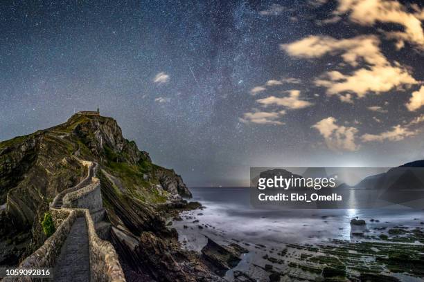 san juan de gaztelugatxe at night with milky way and  matxitxako lighthouse - comunidade autónoma do país basco imagens e fotografias de stock