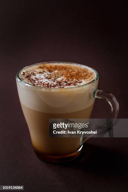 glass of coffee with chocolate topping on elegant dark brown background - capuccino fotografías e imágenes de stock