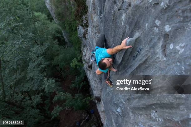 rock climber climbing on the rock wall - persistência imagens e fotografias de stock
