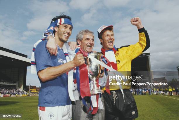 Mark Hateley and Chris Woods of the Rangers FC football team squad celebrate with manager Walter Smith on the pitch with the trophy after beating...