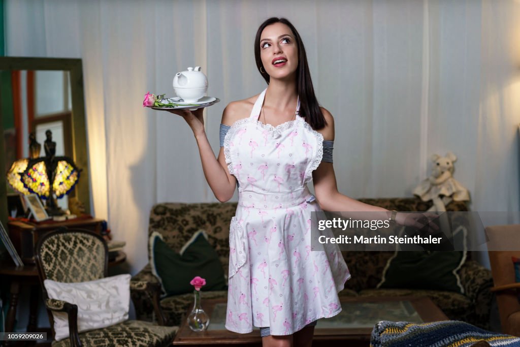 Frau mit Schürze serviert Tee auf einem Tablett