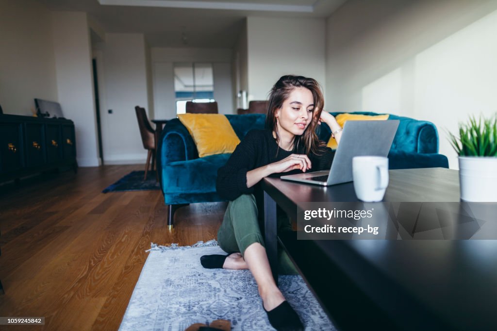 Jovem mulher usando o laptop em casa