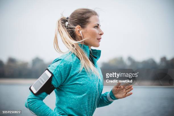 woman running by the lake - female 40 year old beach stock pictures, royalty-free photos & images