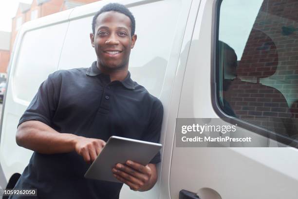 smiling tradesman stood at van using digital tablet - plumber van stock pictures, royalty-free photos & images