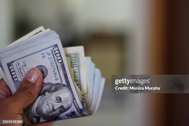 hand holding wad of hundred dollar bills - american one hundred dollar bill stockfoto's en -beelden