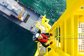 Manual high worker offshore climbing on wind-turbine on ladder