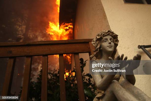 Statue sits on the deck of a burning home as the Camp Fire moves through the area on November 8, 2018 in Paradise, California. Fueled by high winds...