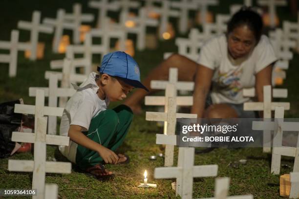 In this photo taken on November 8 a boy and his mother light candles next to crosses to commemorate the fifth anniversary of Super Typhoon Haiyan in...