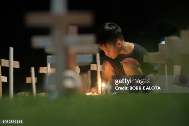 In this photo taken on November 8 a boy lights candle next to crosses to commemorate the fifth anniversary of Super Typhoon Haiyan in Tacloban City,...