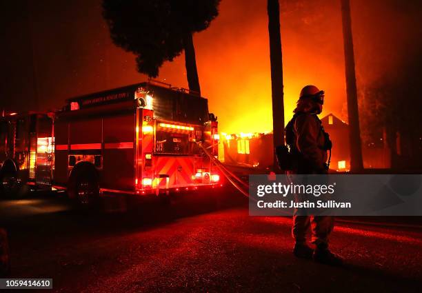 Firefighters try to save a building as the Camp Fire moves through the area on November 8, 2018 in Paradise, California. Fueled by high winds and low...