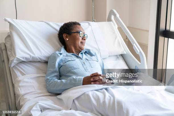 black adult patient lying down on bed hospitalized looking away to the window - hospital bed stock pictures, royalty-free photos & images