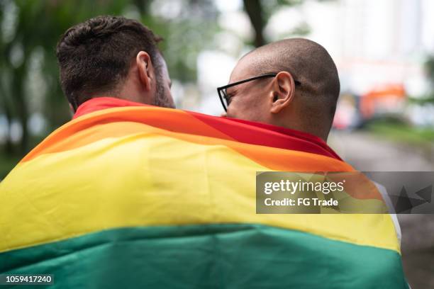 gay getrouwd koppel met regenboogvlag - community engagement stockfoto's en -beelden