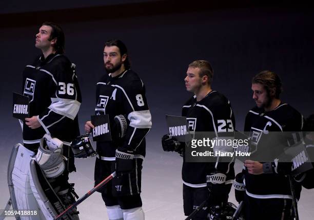 Jack Campbell, Drew Doughty, Dustin Brown and Anze Kopitar of the Los Angeles Kings hold up signs with the word "ENOUGH" in reaction to yeserday's...