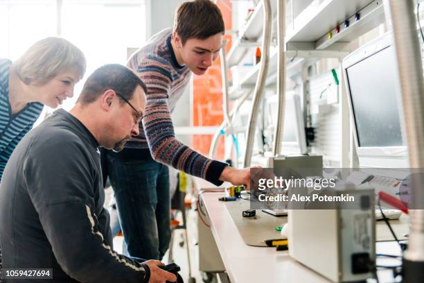 de late tiener jongen uit te leggen hoe een model werkt aan zijn ouders in de engineering laboratorium - science museum stockfoto's en -beelden