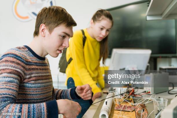 晚十幾歲的男孩和十幾歲的女孩一起在工程實驗室工作 - physics 個照片及圖片檔