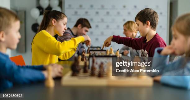 kids of different ages, boys and girls, playing chess on the tournament in the chess club - chess stock pictures, royalty-free photos & images