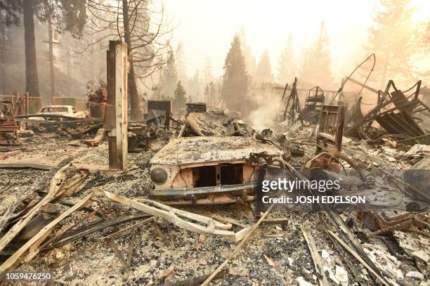 The burned remains of a vehicle and home are seen during the Camp fire in Paradise, California on November 8, 2018. More than one hundred homes, a...