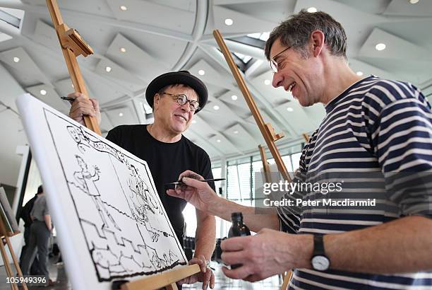 Tim Sanders draws a cartoon watched by fellow cartoonist Michael Heath at the launch of the Big Draw Weekend on October 22, 2010 at City Hall in...