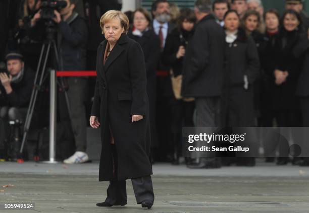 German Chancellor Angela Merkel pauses as she walks across the courtyard of the Chancellery ahead of the arrival of Chilean President Sebastian...