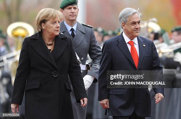 German Chancellor Angela Merkel and Chilean President Sebastian Pinera review an honour guard during a welcoming ceremony at the chancellery in...