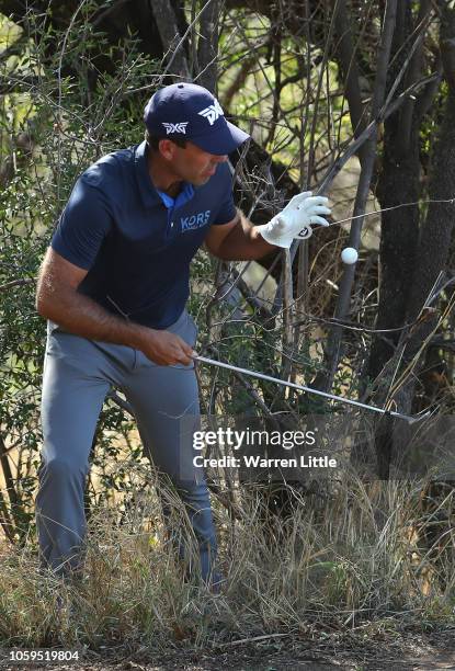 Charl Schwartzel of South Africa picks up a his ball on the 15th hole after taking numerous shots to play out of the trees on the 15th hole,...