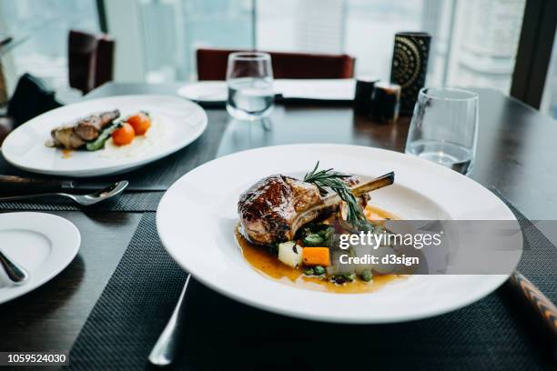 delicate main course of braised lamb chop and steak freshly served on table in a restaurant - lamsrack stockfoto's en -beelden