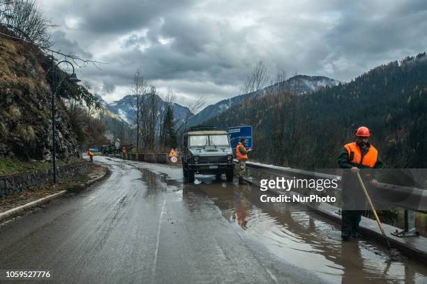 Italian rescuers by 'Protezione Civile' remove debris from the road in the Dolomites Mountains of Colle Santa Lucia, Belluno Province, in Italy,...