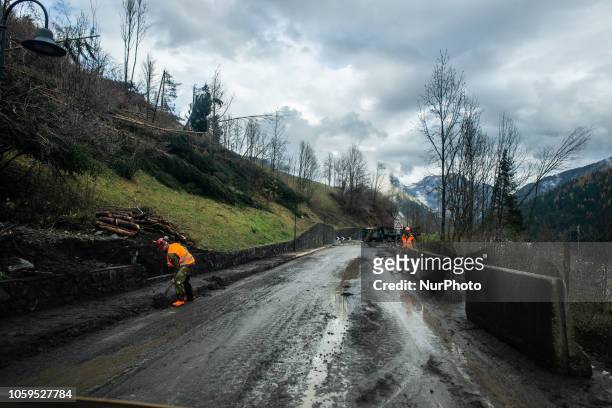 Italian rescuers by 'Protezione Civile' remove debris from the road in the Dolomites Mountains of Colle Santa Lucia, Belluno Province, in Italy,...