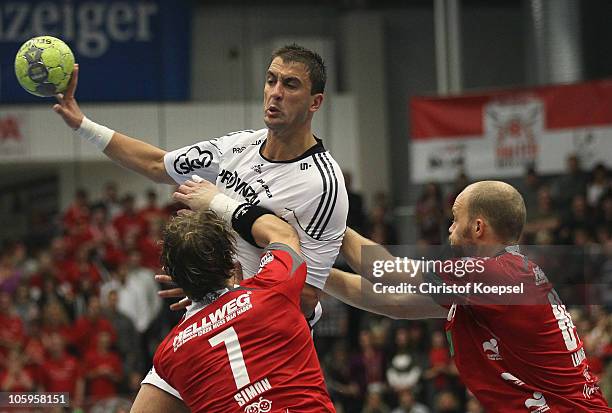 Andreas Simon of Ahlen-Hamm and Thomas Lammers of Ahlen-Hamm challenge Momir Ilic of Kiel during the Toyota Handball Bundesliga match between HSG...