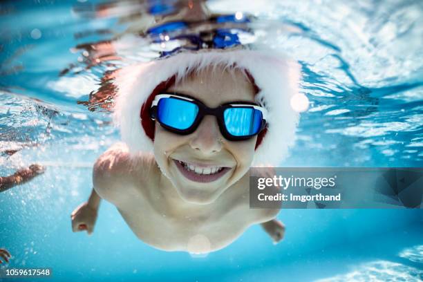 little boy playing in swimming pool during summer christmas - santa swimming stock pictures, royalty-free photos & images