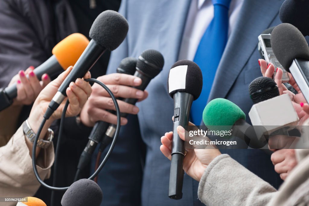 Cropped Hands Of Journalists Holding Microphones In Front Of Businessman
