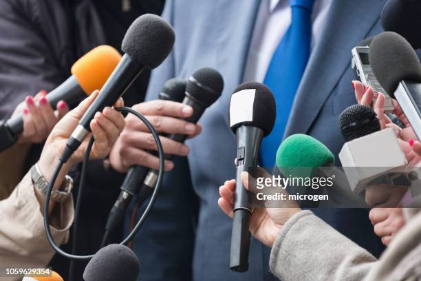 cropped hands of journalists holding microphones in front of businessman - journalism stock pictures, royalty-free photos & images