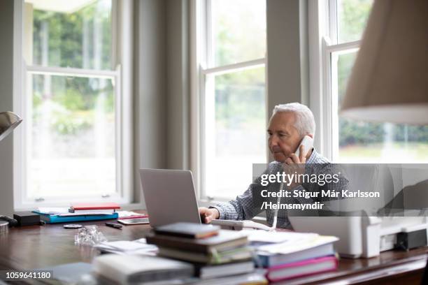 man talking on telephone while surfing on laptop - landline phone home stock pictures, royalty-free photos & images