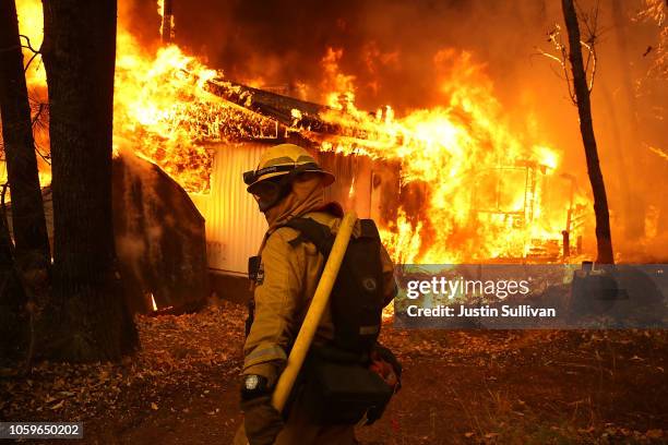 Cal Fire firefighter monitors a burning home as the Camp Fire moves through the area on November 9, 2018 in Magalia, California. Fueled by high winds...