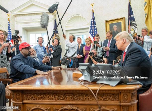 Surrounded by members of the press and others, American rapper and producer Kanye West and retired professional football player Jim Brown talk with...