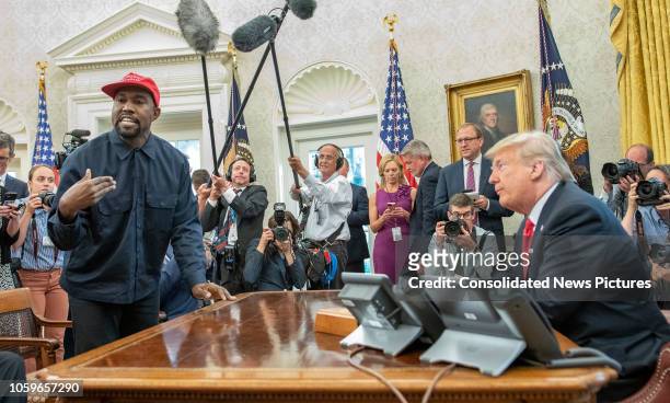 Surrounded by members of the press and others, American rapper and producer Kanye West stands as he talks with real estate developer and US President...