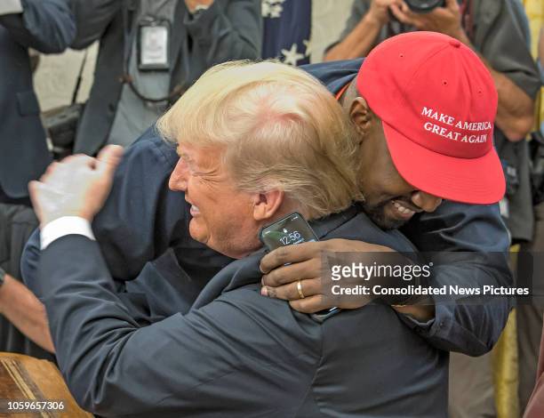 American rapper and producer Kanye West embraces real estate developer and US President Donald Trump in the White House's Oval Office, Washington DC,...