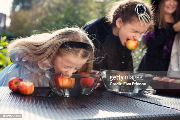 two older children playing halloween bobbing for apples game - dipping stock pictures, royalty-free photos & images