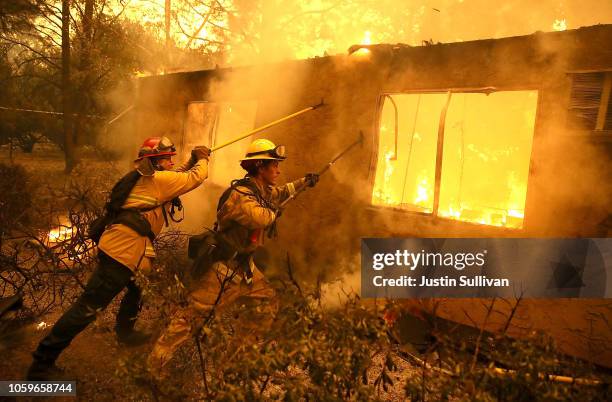 Firefighters try to keep flames from burning home from spreading to a neighboring apartment complex as they battle the Camp Fire on November 9, 2018...