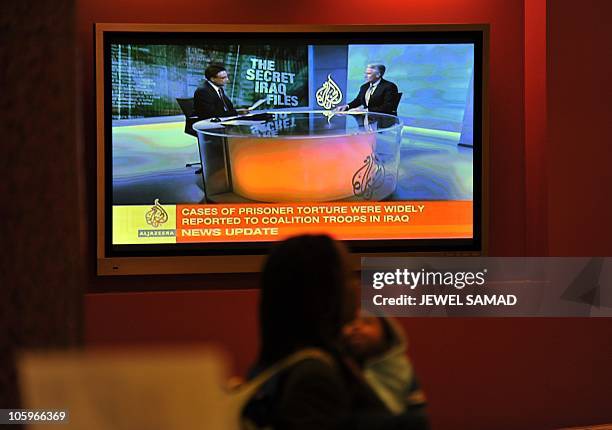 Woman walks past a television set displaying Al-Jazeera news channel telecasting news coverage on secret US documents obtained by WikiLeaks, in...
