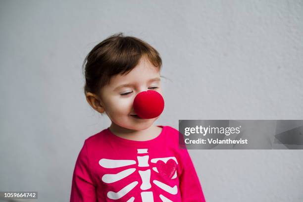 halloween baby girl wearing skeleton costume amb clown red nose - clown nose stock pictures, royalty-free photos & images