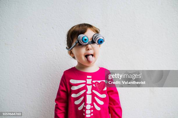 halloween baby girl wearing skeleton costume amb with fake horror eye glasses and tongue out - one baby girl only fotografías e imágenes de stock