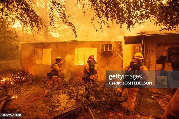 Firefighters push down a wall while battling against a burning apartment complex in Paradise, north of Sacramento, California on November 09, 2018. A...