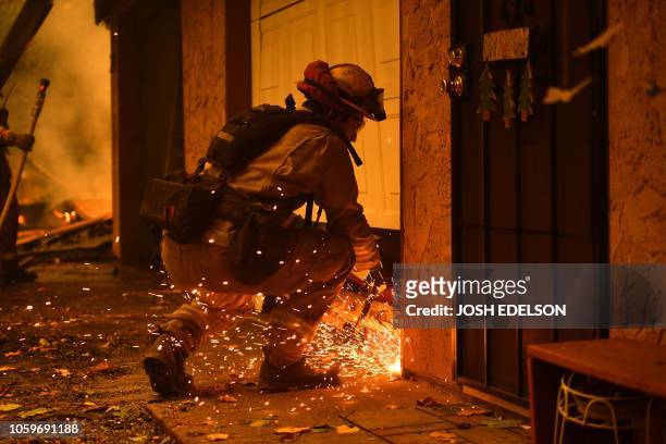 Fireman cuts into a garage door at a burning apartment complex in Paradise, north of Sacramento, California on November 09, 2018. - A rapidly...