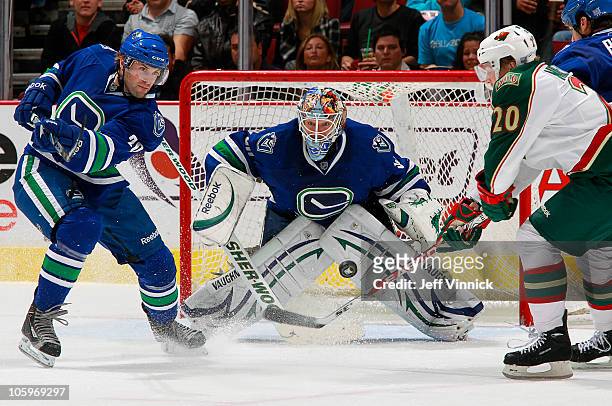 Cory Schneider stops a puck while Ryan Parent of the Vancouver Canucks and Antti Miettinen of the Minnesota Wild fight for the puck in front of him...